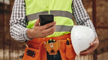 Builder, construction worker using mobile phone