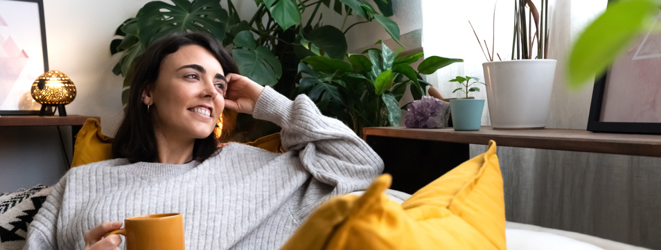 Female homeowner with mug contented on sofa