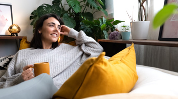 Female homeowner with mug contented on sofa 