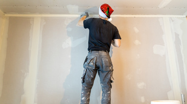 Professional painter in Santa hat applying plaster